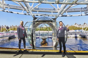 Two twin girls laying on the grass in front of London Eye