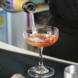 A drink being poured into a cocktail glass at the Eye Lounge Bar