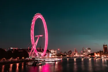 A picture of the London Eye in the night time lit up in pink