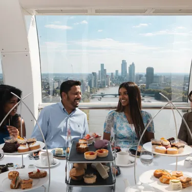 A group of people sitting at a table in the London Eye pod for afternoon tea